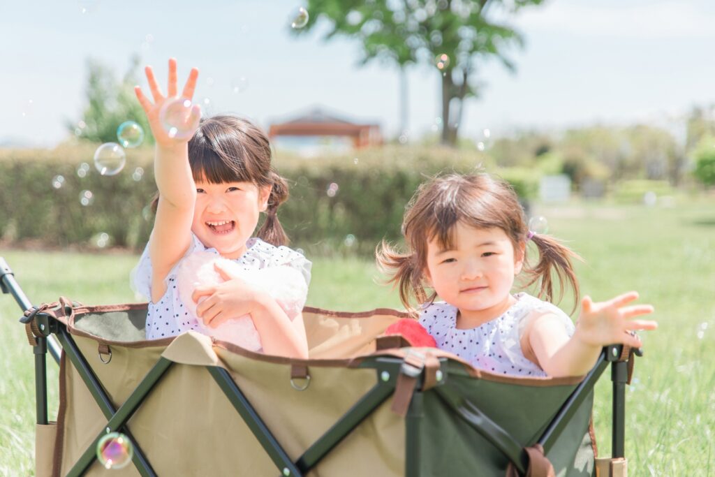 公園でシャボン玉で遊ぶ姉妹の女の子